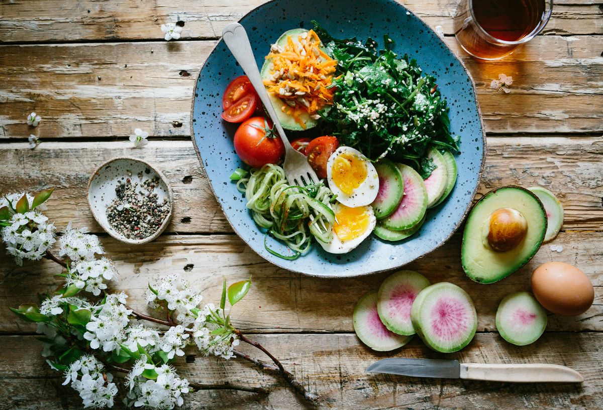 A poached egg, radishes and avocado arranged on a blue plate