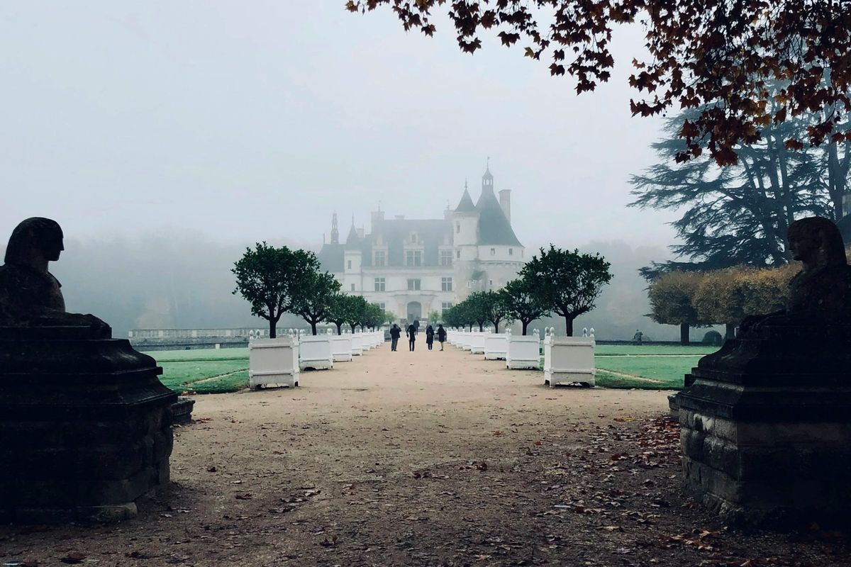 A château at the end of a misty garden avenue in the Loire Valley