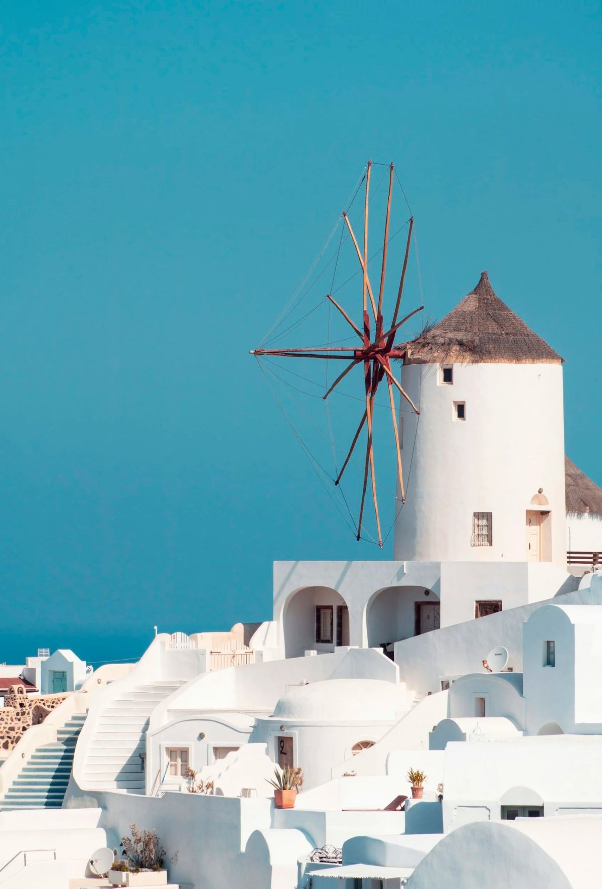 A whitewashed windmill against a turquoise sky
